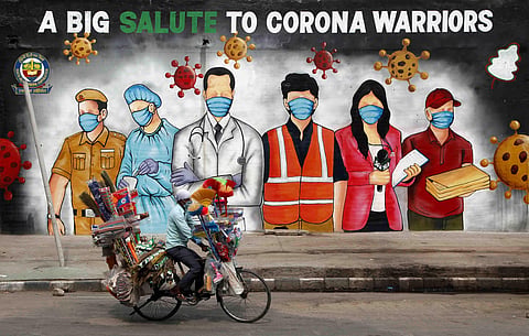 A cyclist paddles infront of a graffiti which is dedicated to corona warriors in New Delhi. (File Photo | Anil Shakya, EPS)