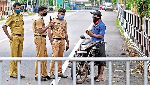 A motorist pleading to the police not to fine him for riding his bike without a valid reason during the triple lockdown. A scene from Vetturoad near Kazhakootam, Thiruvananthapuram. (Photo | B P Deepu, EPS)