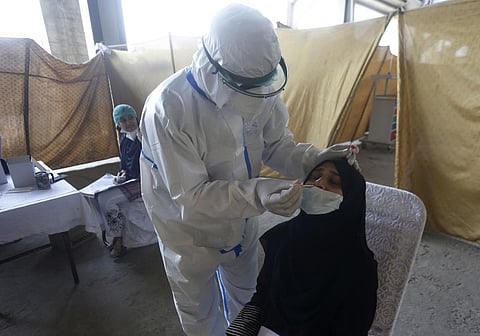 A health worker takes a nasal swab sample at a screening center for the new coronavirus, in Lahore, Pakistan. (Photo| AP)