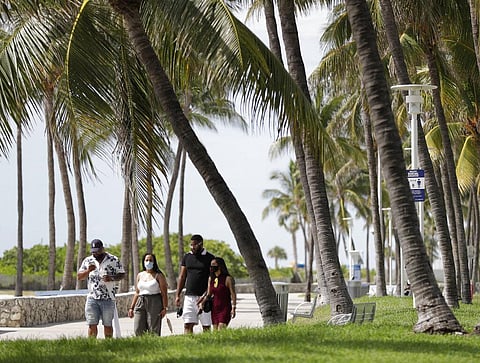 A group of people, wearing face masks to prevent the spread of the coronavirus, walk along a beach path on Miami Beach, Florida's famed South Beach (Photo | AP)