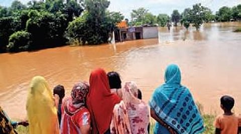 People watch as flood water gushes into Mirjapur village of Dasarathpur block