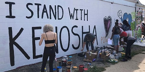 Volunteers paint murals on boarded-up businesses in Kenosha at an Uptown Revival. (Photo | AP)