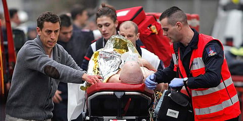 In this Jan. 7, 2015 photo, an injured person is transported to an ambulance after a shooting at the French satirical newspaper Charlie Hebdo's office, in Paris.