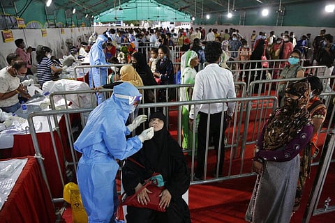 A health worker takes a nasal swab sample of a passenger for COVID-19 test at a facility erected at a railway station to screen people coming from outside the city, in Ahmedabad, India. (Photo | AP)