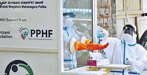 A technician sanitises the gloves used for collecting swab samples at a fever clinic in Bengaluru on Friday | meghana Sastry