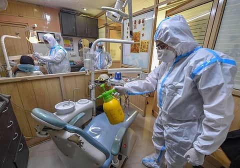 A dentist wearing a PPE kit sanitizes a chair inside a clinic during Unlock 4 at Jheel Khurenja in East Delhi Saturday Sept. 26 2020. (Photo | PTI)