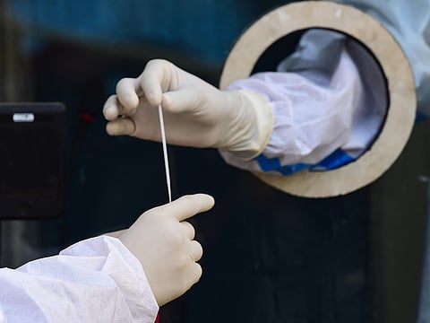A health worker collects swab sample in a tube for the COVID-19 test at Rajiv Gandhi hospital in New Delhi Tuesday. (Photo | PTI)