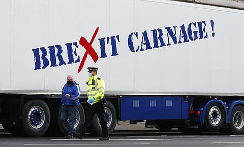A policeman escorts the driver of a shellfish export truck as he is stopped for an unnecessary journey in London. (Photo | AP)