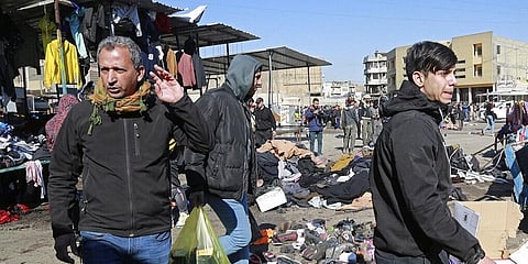 People and security forces gather at the site of a deadly bomb attack in Baghdad, Iraq. (Photo | AP)