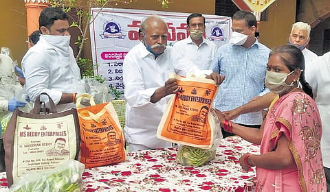 Retired principal Ramachandra Reddy distributing essential commodities to the needy in Kadapa I Express