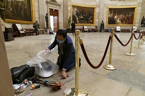 Rep. Andy Kim, D-N.J., cleans up debris and personal belongings strewn across the floor of the Rotunda in the early morning hours of Thursday, Jan. 7, 2021. (Photo | AP)