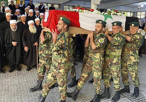 Volunteers from the Baath battalions carry the Syrian flag-wrapped coffin of former Syrian Druze lawmaker Midhat Saleh, allegedly shot by Israeli sniper fire (Photo | AP)