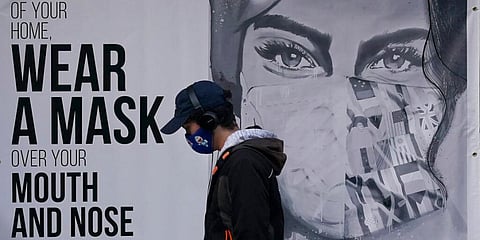 A pedestrian walks past a mural reading: 'Wear a mask over your mouth and nose,' during the coronavirus outbreak in San Francisco. (Photo | AP)
