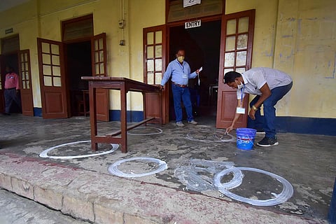 A polling officer draws markers on a floor to ensure social distancing on the eve of the second phase of Assam assembly polls. (File Photo | PTI)