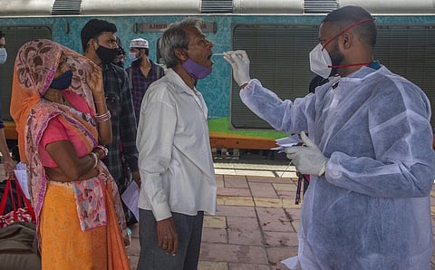 A health worker takes a swab sample of a traveler to test for COVID-19 at a train station in Mumbai. (File photo| AP)