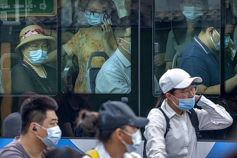 People wearing face masks to protect against COVID-19 ride on a bus during the morning rush hour in Beijing. (File photo | AP)