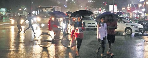 People cover themselves with umbrellas during rains that lashed Bhubaneswar. (Photo| Irfana, EPS)