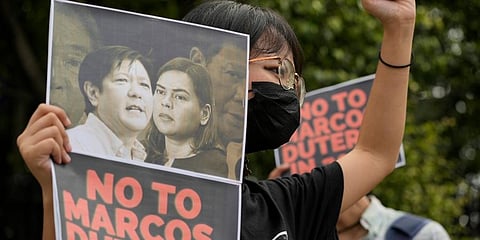 A protester holds a photo bearing the photos of the late dictator's son, Ferdinand Marcos Jr. (L) and Davao city Mayor Sara Duterte during a protest in Quezon city, Philippines. (Photo | AP)