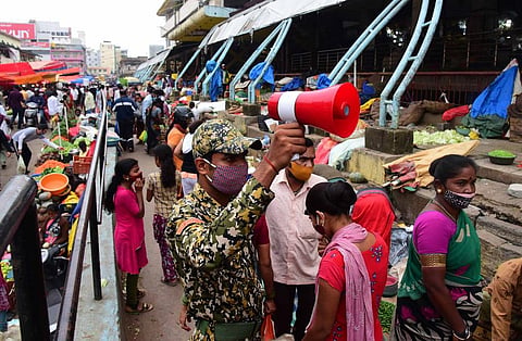 A BBMP marshal creates awareness among shoppers on the need to follow Covid-appropriate behaviour near KR Market. (Photo| Shriram BN, EPS)