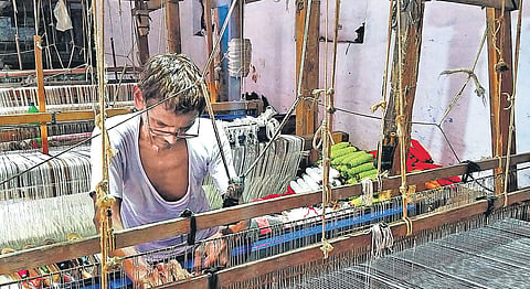 A Khes weaver weaving on a handloom.