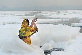 A woman prays in polluted Yamuna river.