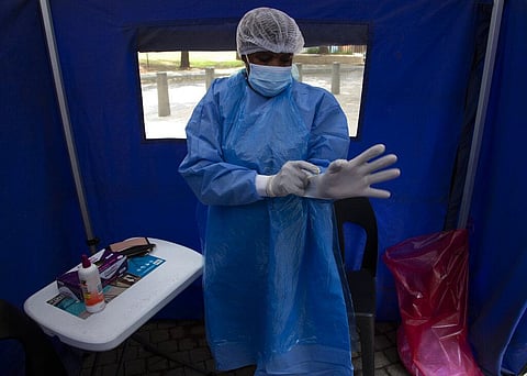 A healthcare worker prepares to test a person for COVID-19 at a facility in Soweto, South Africa. (Photo | AP)