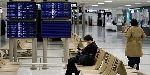 A passenger rests near arrival information screens for international flights at the Narita International Airport in Narita, east of Tokyo, Thursday, Dec. 2, 2021. (Photo | AP)