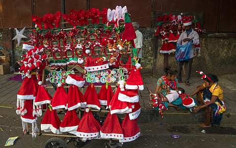 A woman feeds her child on the side of a road, as she waits for customers to buy decorative items for the Christmas from her mobile shop, in Mumbai. (Photo | AP)