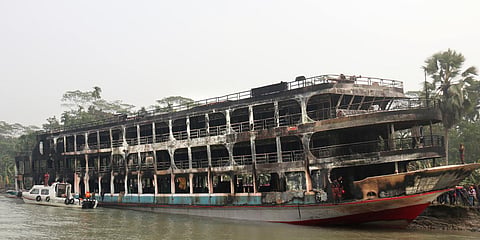 A burnt passenger ferry is seen anchored off the coast of Jhalokati district on the Sugandha River in Bangladesh. (Photo| AP)