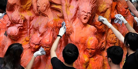 University students clean the 'Pillar of Shame' statue, a memorial for those killed in the 1989 Tiananmen crackdown, at the University of Hong Kong. (Photo | AP)