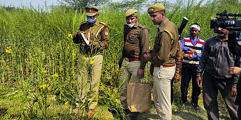 Police personnel investigate at the site where bodies of two minor Dalit girls were found in a field and another in critical condition (Photo | PTI)