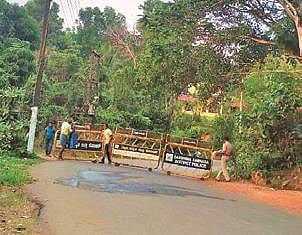 Police personnel place barricades on a road linking Dakshina Kannada with Kerala in Bantwal taluk