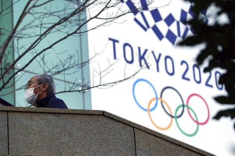 A man wearing a protective mask to help curb the spread of the coronavirus walks near the banner for the Tokyo 2020 Olympic Games Thursday, Feb. 25, 2021, in Tokyo. (Photo | AP)