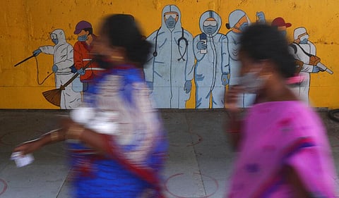 Women walk past a graffiti honoring those on the frontlines in the fight against the coronavirus outside a train station in Mumbai. (File Photo | AP)