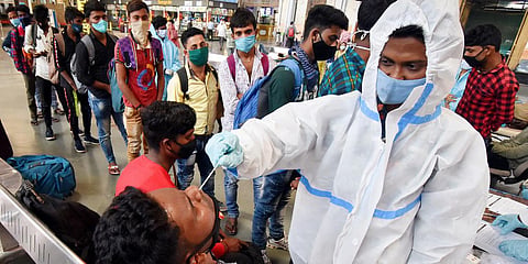 A healthcare worker takes a swab sample of a passenger for the COVID-19 test at Chhatrapati Shivaji Maharaj Terminus, in Mumbai. (Photo| ANI)