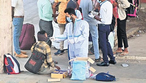 A health worker clad in PPE kit collects swab samples of passengers at the KSR railway station in Bengaluru from on Sunday | ashishkrishna HP