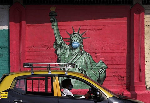 A taxi drives past a mural of the Statue of Liberty wearing a face mask to stress on the importance of face masks to fight the coronavirus, in Mumbai. (Photo | AP)