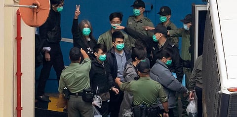 Former lawmaker Leung Kwok-hung (Second L) shows a victory sign and some of the 47 pro-democracy activists are escorted by CS officers to a prison van in Hong Kong. (Photo | AP)