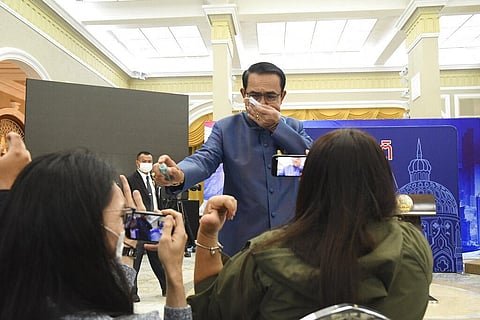 Thailand's Prime Minister Prayuth Chan-ocha sprays alcohol mist on a front row of reporters sitting inside the press conference room at Government house in Bangkok. (Photo | AP)