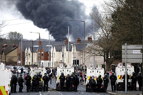 Police form a line on the Springfield road to stop Nationalists and Loyalists attacking each other, as a hijacked bus burns in the distance in Belfast. (File Photo | AP)