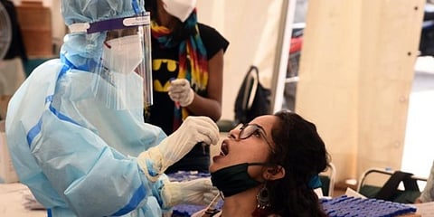 A health worker in PPE kit collects a swab sample from a traveller at Anand Vihar ISBT during coronavirus screening. (Photo | Parveen Negi, EPS)