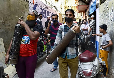 People carry empty 0xygen cylinders for free refilling provided by Residence Welfare Association (RWA) of Turkman Gate, as COVID-19 case spike in New Delhi. (Photo | PTI)