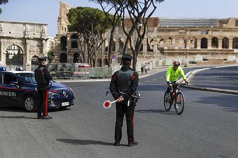 A cyclist rides past Carabinieri police officers at road block near the Colosseum, in downtown Rome, Saturday, April 3, 2021. (Photo | AP)