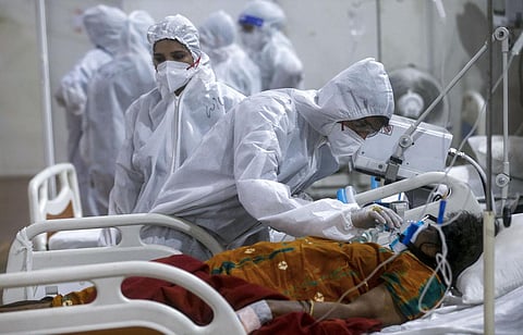 A health worker tries to adjust the oxygen mask of a patient at the BKC jumbo field hospital, one of the largest COVID-19 facilities in Mumbai. (Photo | AP)