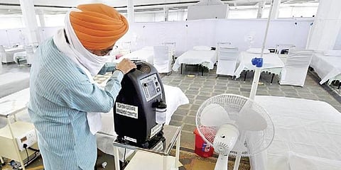 A volunteer checks an oxygen concentrator machine.