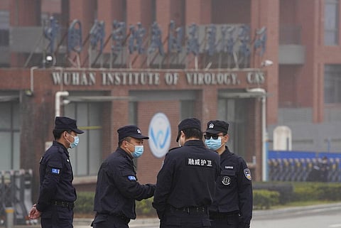 Security personnel gather near the entrance of the Wuhan Institute of Virology during a visit by the World Health Organization team. (Photo | AP)