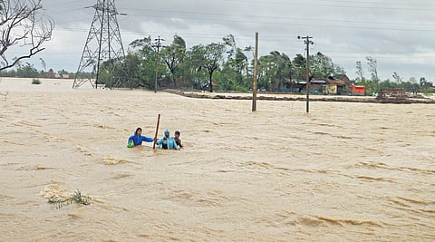 A family wades through waist-deep water to reach a safer place near Dhamra port in Bhadrak that was battered by cyclone Yaas