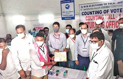 Newly elected TRS legislator Nomula Bhagath receives the certificate of election from the polling officer, after completion of counting, on Sunday