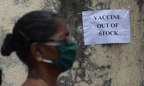 A woman wearing mask walks past a notice about the shortage of coronavirus (COVID-19) vaccine supply outside a vaccination centre. (Photo | AP)