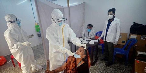 A health worker takes swab sample of a woman for COVID-19 test, at a railway station in Agartala. (Photo | PTI)